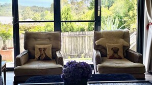 A room with two armchairs facing a large window overlooking a garden.