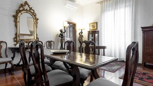 Une salle à manger avec une table en bois, des chaises, un grand miroir décoratif et un buffet.