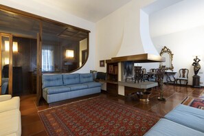 A living room with a blue sofa, a wooden cabinet, a large mirror, and a patterned rug.