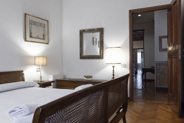 A hotel room with a wooden bed, two bedside tables, a mirror, and a lamp.