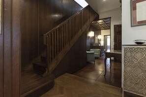 A wooden staircase leading to an upper floor, a dining area with a table and chairs, and a kitchen area with a sink and countertop.