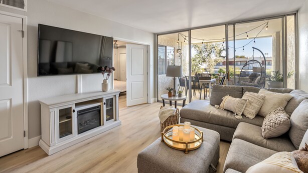 Uma sala de estar moderna com televisão de tela plana, lareira, sofá e área de jantar com mesa e cadeiras.