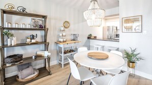 Cozinha moderna com armários brancos, uma mesa de jantar de madeira e um lustre.