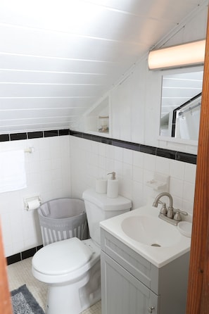 A bathroom with a white toilet, a sink, and a trash can.