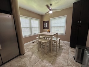 A kitchen with a dining table, chairs, a ceiling fan, and a trash can. - Near FSU | Sleeps 12 | Free Parking + EV Charger (Tallahassee)