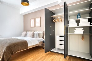 A bedroom with a bed, a wardrobe with hanging space, and a bedside table. - Hip Langstrasse 2.5 Room w/ Storage & W/D, 2 min to Market, by Blueground (Zurich)