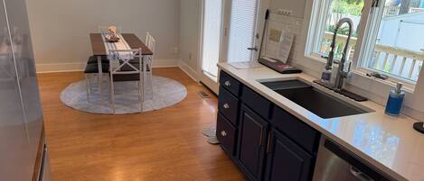 A kitchen with a stainless steel dishwasher, a sink with a faucet, and a window with blinds.