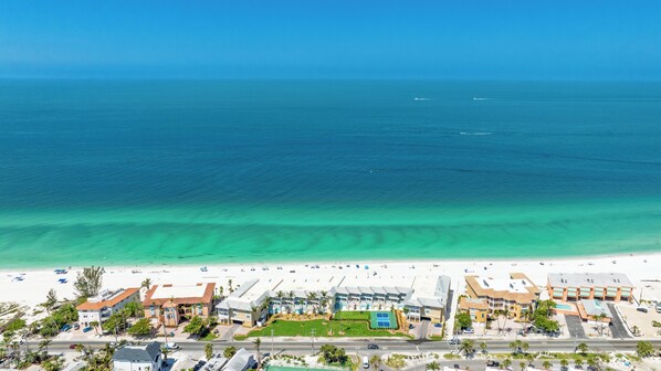 A coastal hotel with a beach view, multiple buildings, and a clear blue ocean.