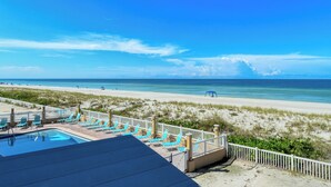 Vista de una playa con zona de piscina, sillas de descanso y una playa de arena.