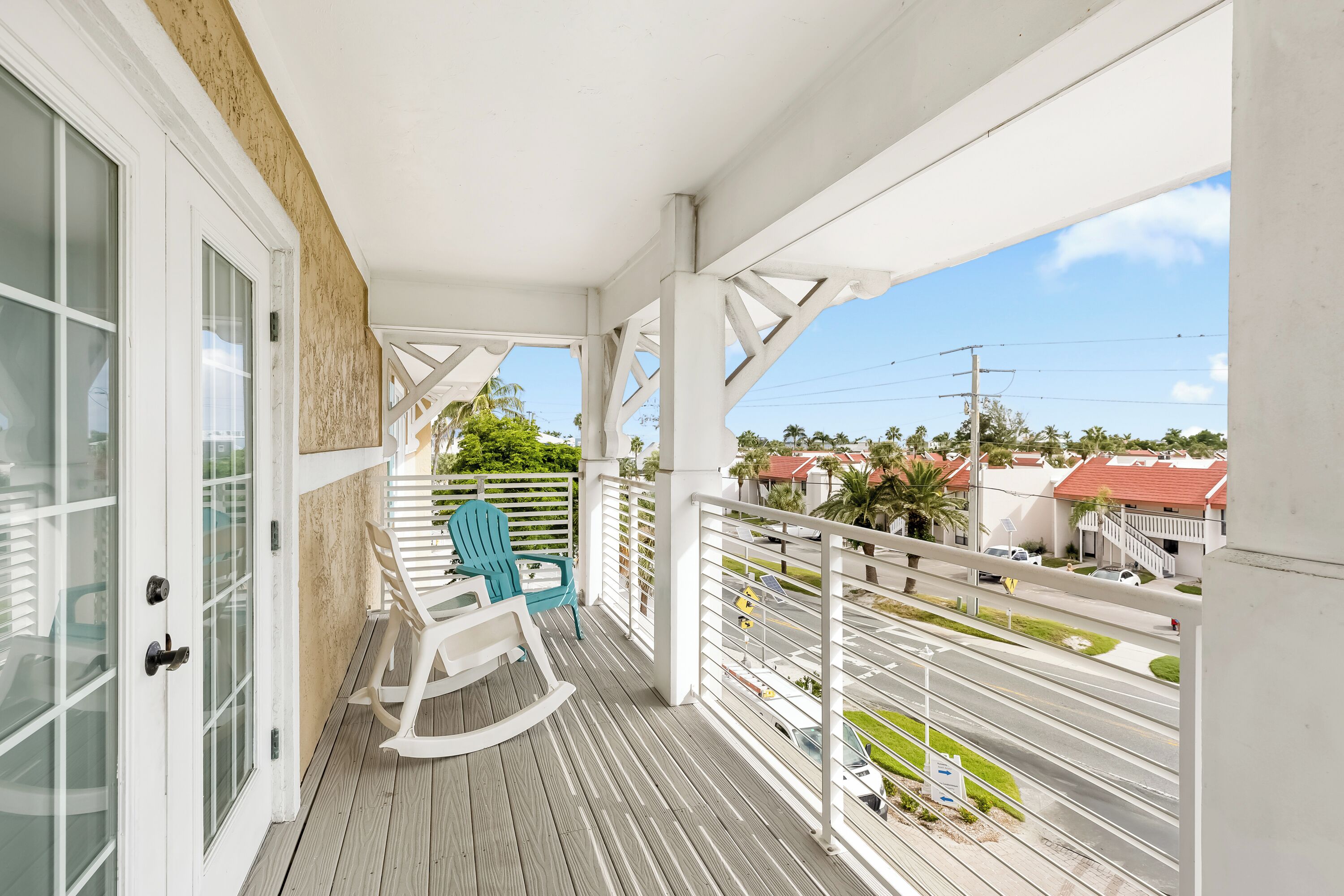 A balcony with a rocking chair and a view of the street.
