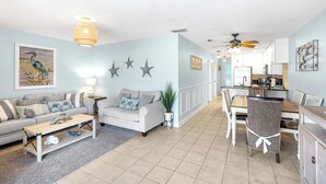 A spacious living room with a sofa, coffee table, and dining area. - Welcome to paradise! Direct beach access, summer and fall dates available!! (Bradenton Beach)
