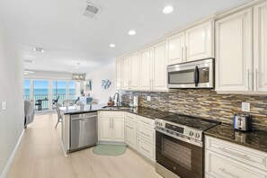 A modern kitchen with white cabinets, stainless steel appliances, and a view to the outside.