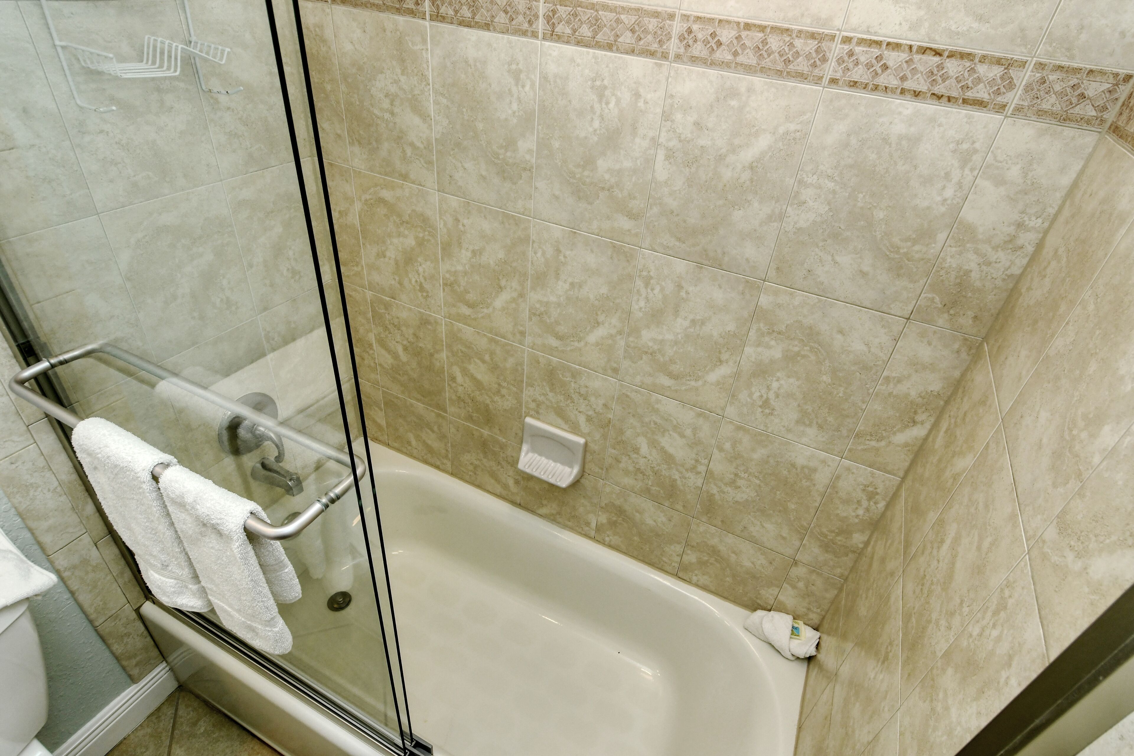 Un baño con cabina de ducha de vidrio, bañera y retrete.