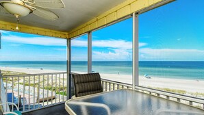 A balcony with a view of the beach, a table, and chairs. - Beautiful beachfront views!  Direct beach access! (Bradenton Beach)