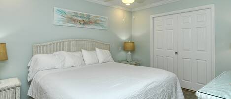 Un dormitorio con una cama grande, un ventilador de techo, una puerta y una obra de arte colgada en la pared.