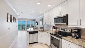 Una cocina moderna con armarios blancos, electrodomésticos de acero inoxidable y vistas al exterior.