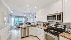 Una cocina moderna con armarios blancos, electrodomésticos de acero inoxidable y vistas al exterior.