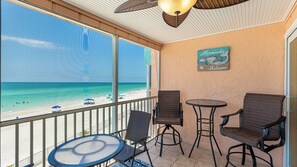 A balcony with a view of the beach, wicker chairs, a small round table, and a 'Mermaids Welcome' sign. - Beautiful Gulf View 2/2!! Stunning sunsets every night! (Bradenton Beach)