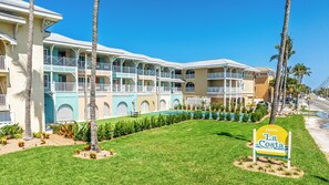 Un hotel de varios pisos con balcones, piscina y palmeras.