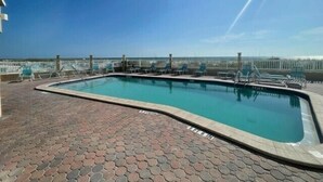 A rooftop pool with a clear view of the beach, surrounded by lounge chairs and a fence. - Peak a boo Gulf of Mexico balcony views! Direct beach access! Summer and fall dates available! (Bradenton Beach)