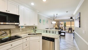 A modern kitchen with white cabinets, a stainless steel dishwasher, and a granite countertop. - Peak a boo Gulf of Mexico balcony views! Direct beach access! Summer and fall dates available! (Bradenton Beach)