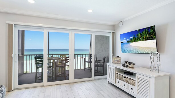 Ein Balkon mit Meerblick, ein Esstisch mit Stühlen und ein Fernseher an der Wand.