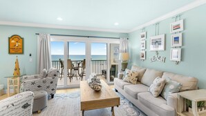 A living room with a view to the beach, a sofa, chairs, a coffee table, and a lamp. - Beautiful Beach and sunset views alongside direct beach access! (Bradenton Beach)