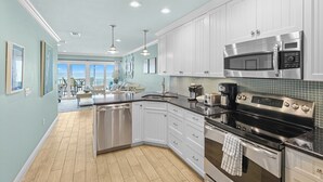 A modern kitchen with white cabinets, stainless steel appliances, and a view to the outside. - Beautiful Beach and sunset views alongside direct beach access! (Bradenton Beach)