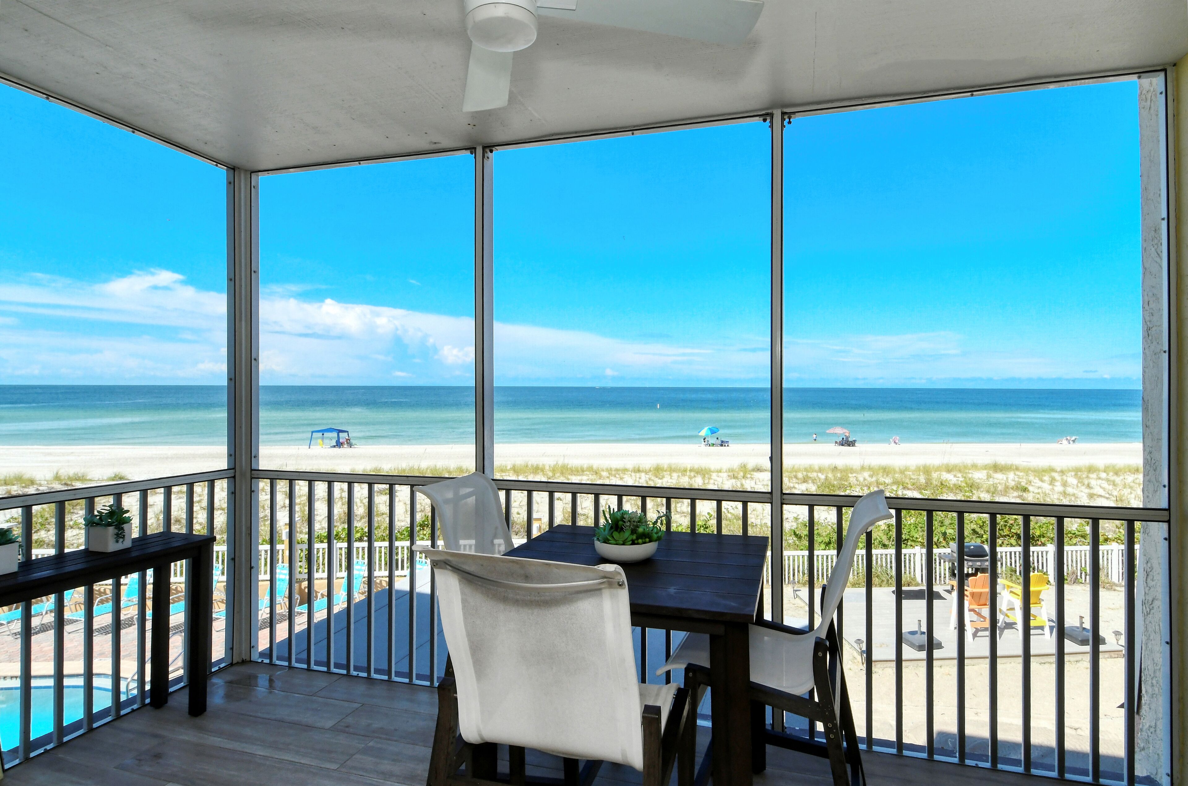 A covered balcony with a view of the beach and ocean.