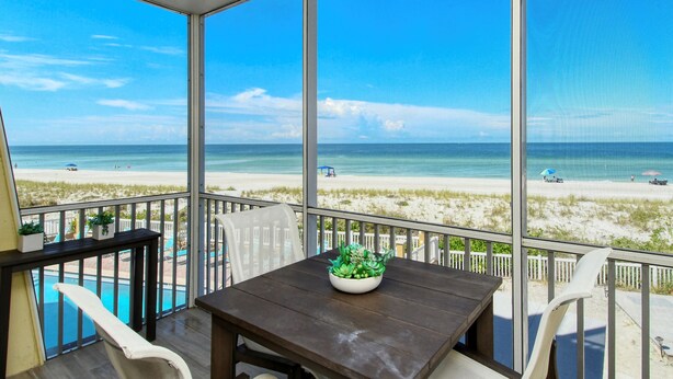Ein Balkon mit Blick auf den Strand, ein Tisch mit einer Pflanze und ein Schwimmbecken.