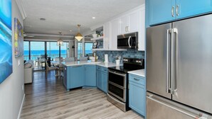 Eine moderne Küche mit blauen Schränken, Edelstahlgeräten und Blick ins Freie.