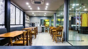 A modern restaurant with wooden tables and chairs, a marble wall, and a glass partition. - The Riva Vientiane Hotel (Vientiane)