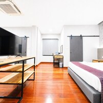 Ein Hotelzimmer mit Bett, Schreibtisch, Stuhl, Fernseher und einer Schiebetür.