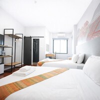 A hotel room with two beds, a desk, a wardrobe, and a shower.