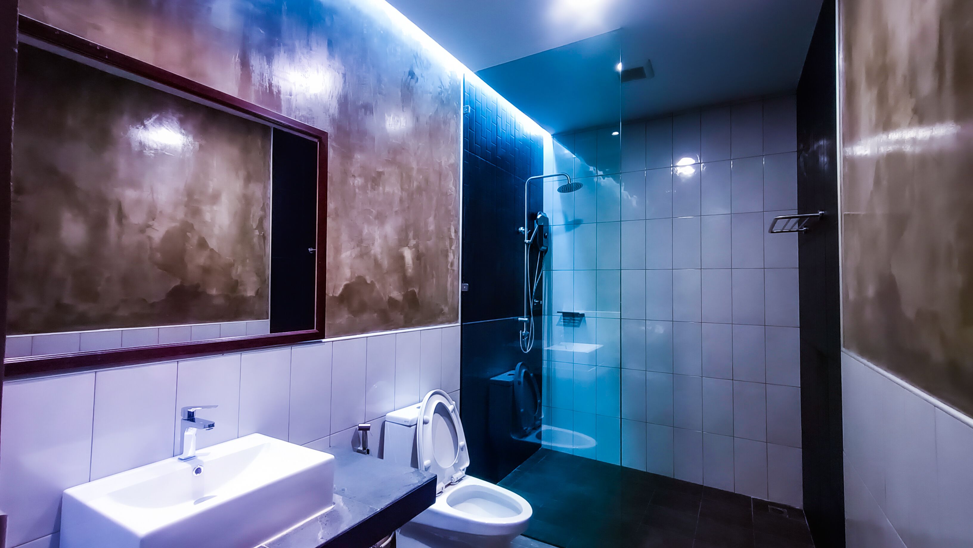Ein modernes Badezimmer mit einem großen Spiegel, einem Waschbecken, einer Toilette und einer Duschkabine.