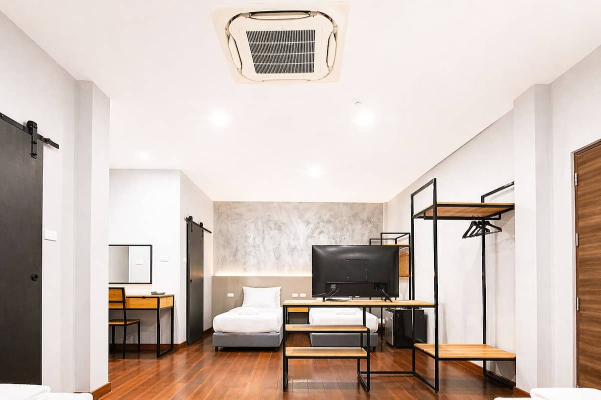 A modern hotel room with a bed, desk, TV, and a wardrobe.