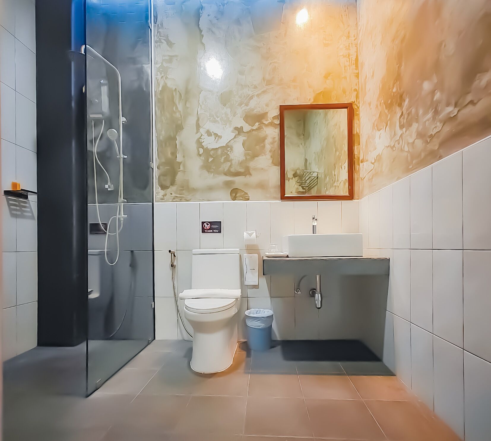 A modern bathroom with a glass-enclosed shower, a white toilet, and a sink with a mirror above it.