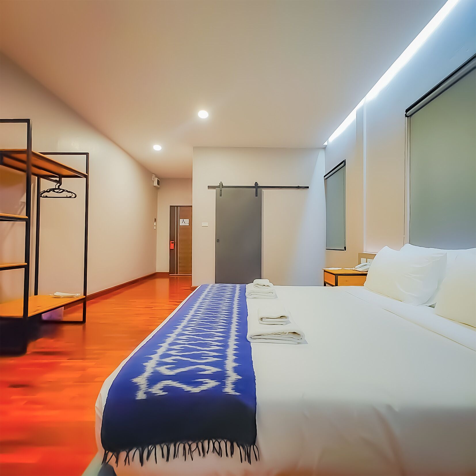 Une chambre d’hôtel avec un lit, un bureau, une armoire et un miroir.