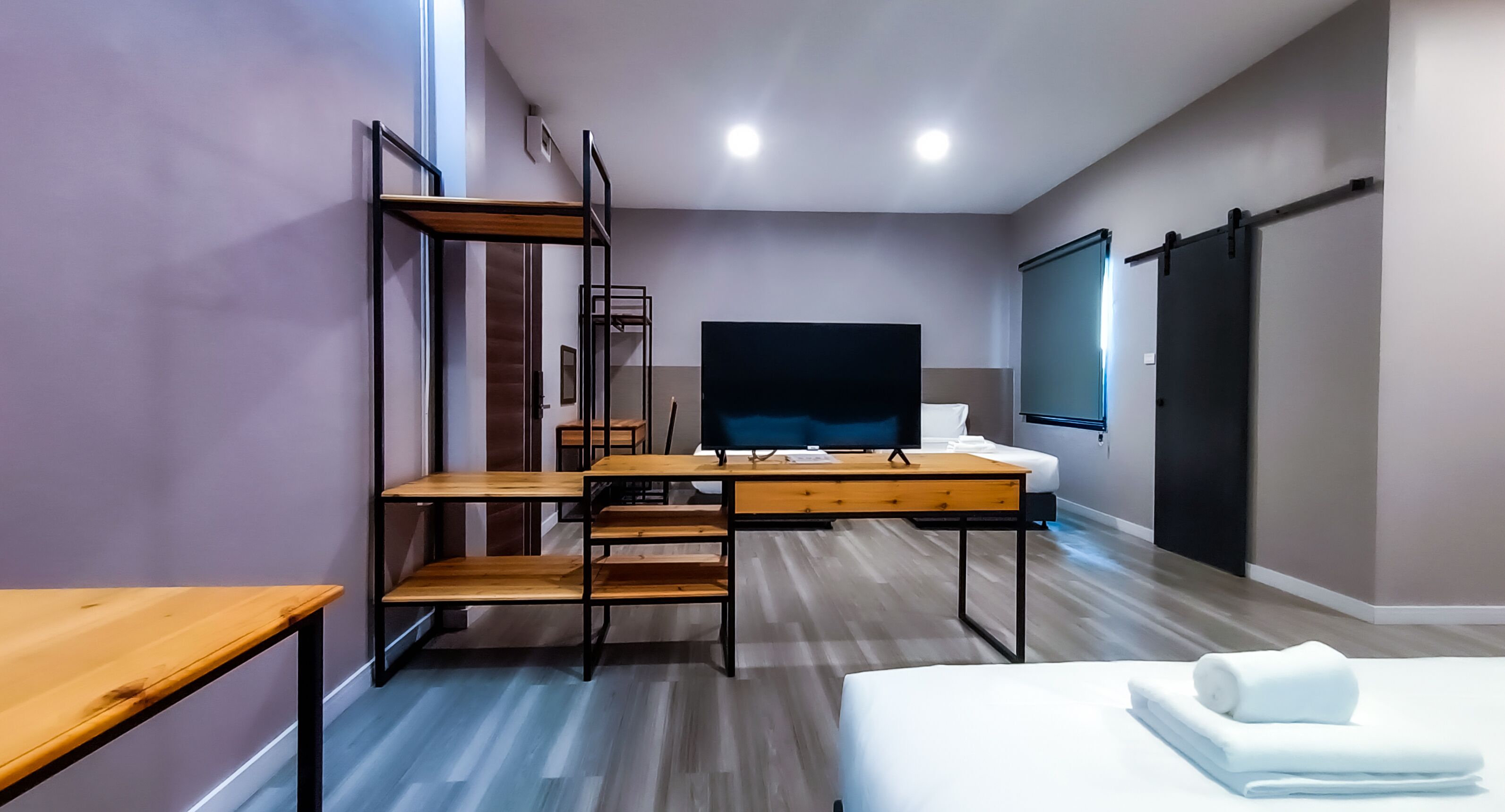 Una habitación de hotel moderna con cama, escritorio, televisor y balcón.