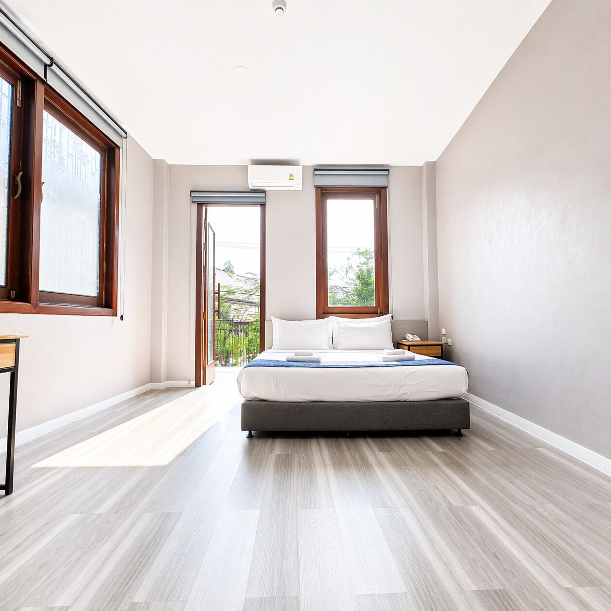 A bedroom with a bed, a desk, and a window.