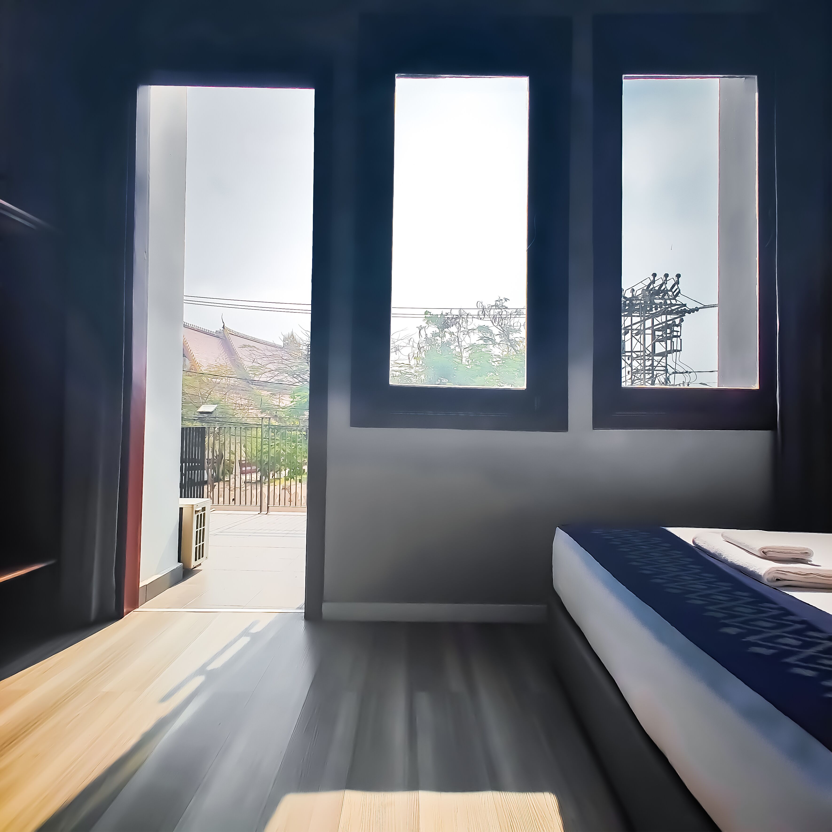 A room with a bed, a window, and a view of the outside.