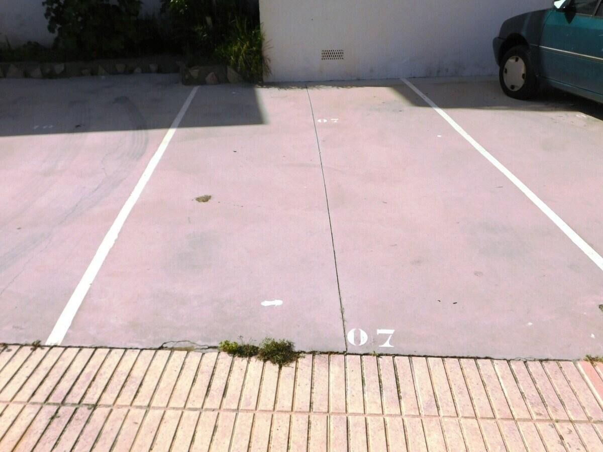 A parking lot with marked spaces and a curb.