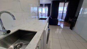 A modern kitchen with white marble countertops, stainless steel appliances, and a double sink. - Exodus Dandenong Apartment Hotel (Dandenong)