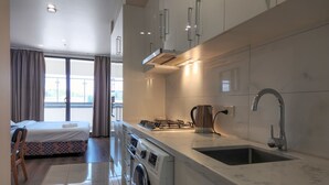 A modern kitchen with a built-in washing machine, a kettle, and a sink. - Exodus Dandenong Apartment Hotel (Dandenong)