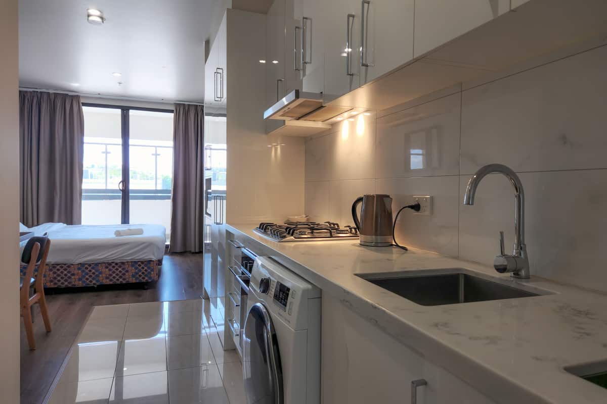 A modern kitchen with a built-in washing machine, a kettle, and a sink.