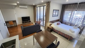 A hotel room with a bed, a sofa, a TV, a desk, and a bathroom. - Exodus Dandenong Apartment Hotel (Dandenong)