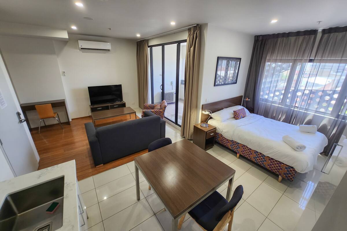 A hotel room with a bed, a sofa, a TV, a desk, and a bathroom.