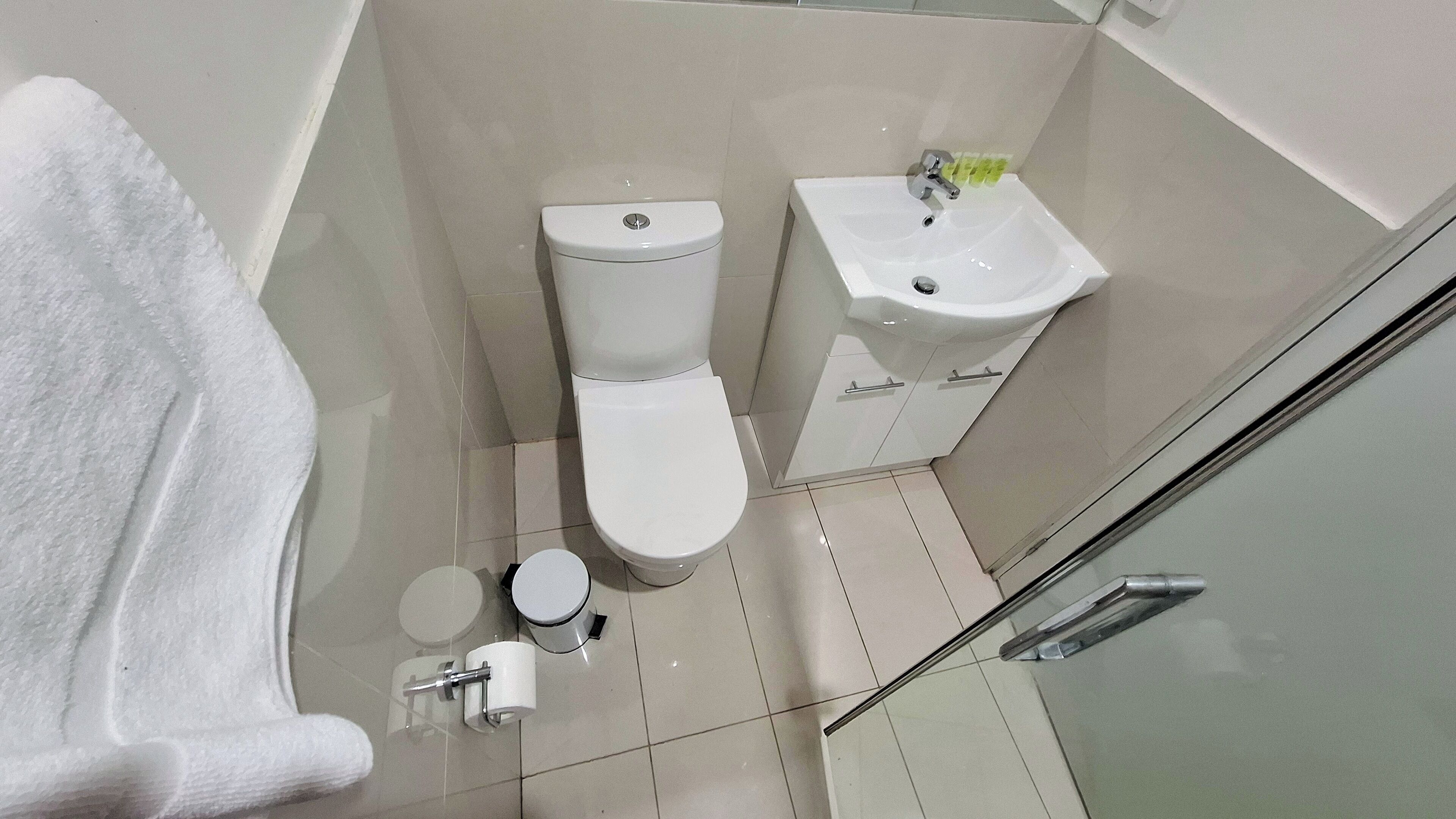 Un baño con inodoro, lavabo y mampara de vidrio.