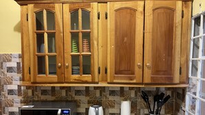 Una cucina con mobili in legno, un forno a microonde, un bollitore e un portarotolo di carta.