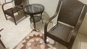 Una stanza con due poltrone in vimini, un tavolino in vetro e un tappeto decorato.